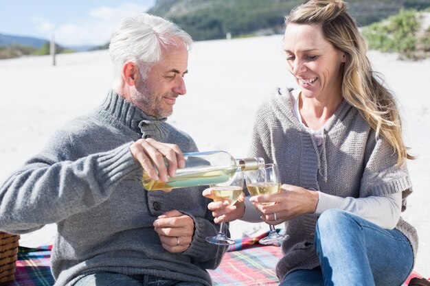 Pareja disfrutando de vino blanco en picnic en la playa