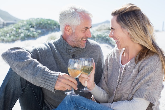 Pareja disfrutando de vino blanco en picnic en la playa