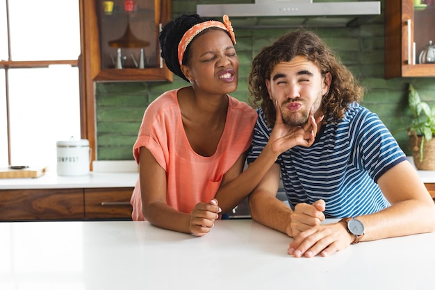 Una pareja diversa una joven afroamericana pellizca juguetonamente la mejilla de un joven caucásico