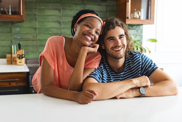 Una pareja diversa sonríe cálidamente apoyándose en un mostrador de la cocina