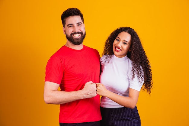 Foto pareja de diversidad celebrando sobre fondo amarillo con espacio para texto. pareja sobre fondo amarillo