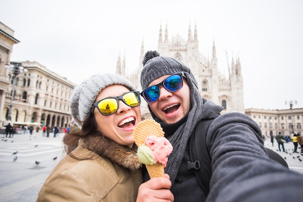 Pareja divertida teniendo autorretrato con helado en el Duomo de Milán