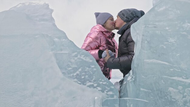 La pareja se divierte caminando en invierno contra el fondo del hielo del lago congelado Los amantes se acuestan en el hielo claro con grietas se divierten besan y abrazan Vista desde arriba Gente feliz en el hielo cubierto de nieve Historia de amor de luna de miel