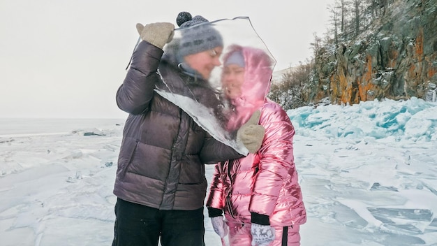 La pareja se divierte durante la caminata de invierno contra el fondo del hielo de f