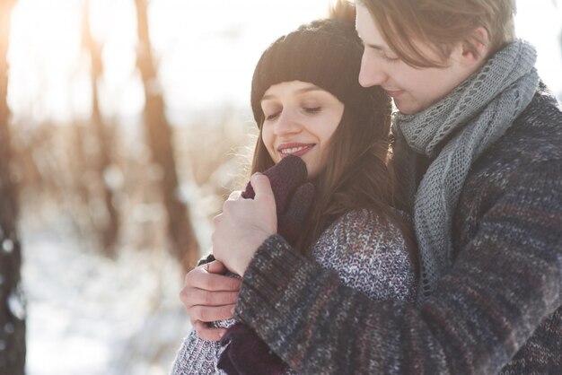 La pareja se divierte y se ríe. Beso. Pareja joven inconformista abrazándose en el parque de invierno. Historia de amor de invierno, una hermosa joven pareja elegante. Concepto de moda de invierno con novio y novia