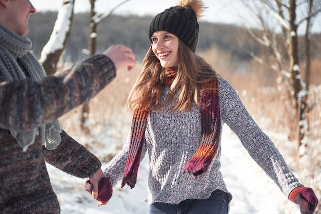 La pareja se divierte y se ríe. Beso. Pareja joven inconformista abrazándose en el parque de invierno. Historia de amor de invierno, una hermosa pareja joven y elegante. Moda de invierno con novio y novia