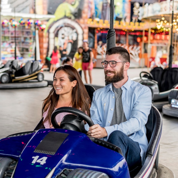 Pareja divirtiéndose con autos chocadores en el parque