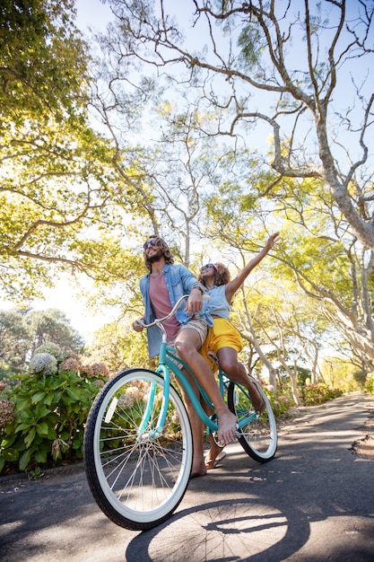 Pareja divirtiéndose mientras andas en bicicleta en el parque