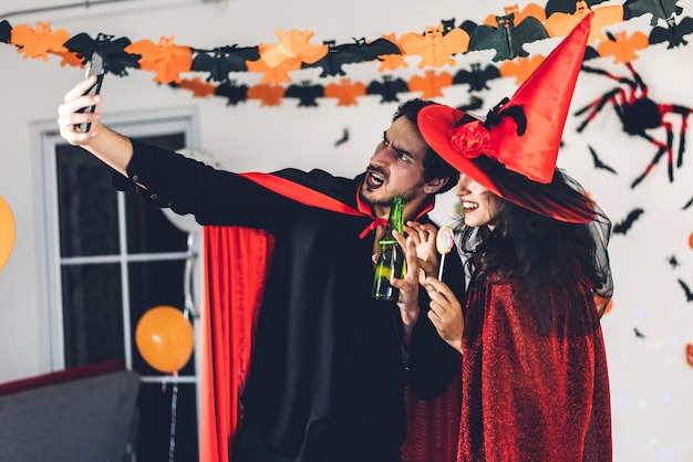 Pareja divirtiéndose sosteniendo calabazas y vistiendo disfraces de carnaval vestidos de halloween