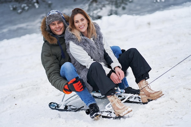 Pareja divirtiéndose con trineo sobre la nieve en la nieve del invierno. Foto de alta calidad