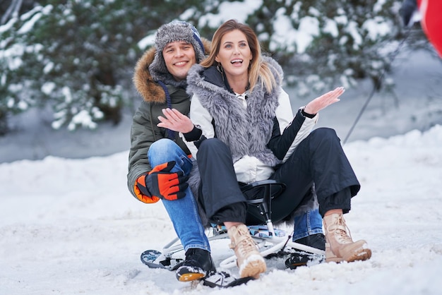 Pareja divirtiéndose con trineo sobre la nieve en la nieve del invierno. Foto de alta calidad