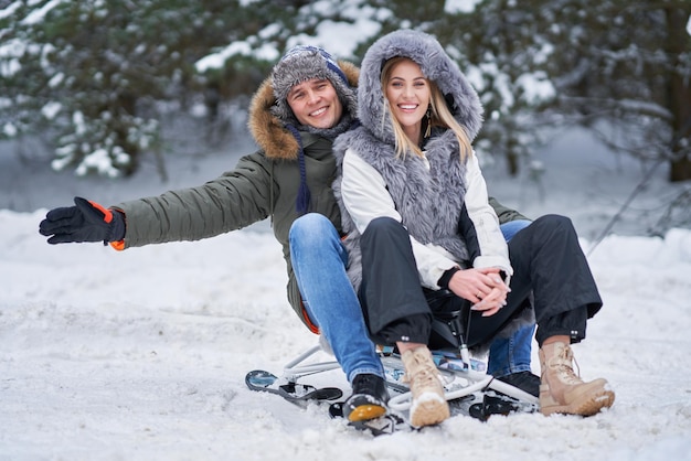 Pareja divirtiéndose con trineo sobre la nieve en la nieve del invierno. Foto de alta calidad