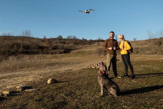 Foto pareja con drone y perro full shot