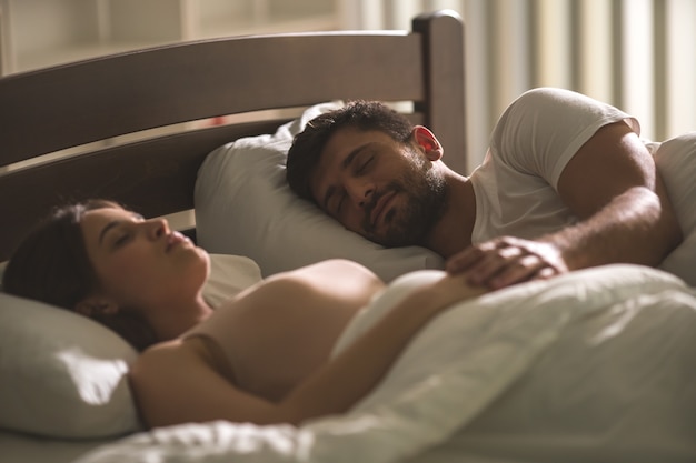 Foto la pareja durmiendo en la cómoda cama.