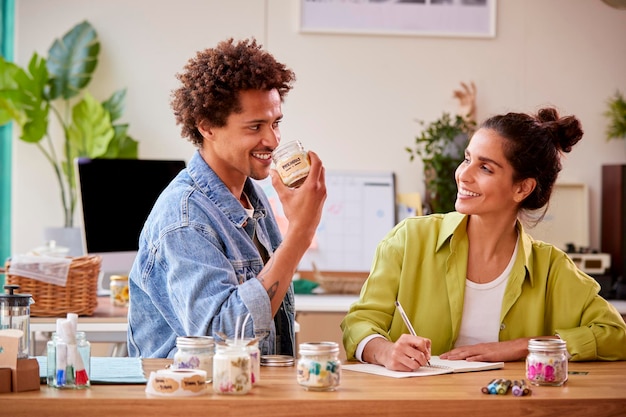 Pareja ejecutando negocios en línea haciendo velas de boutique en casa con olor a producto