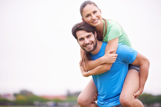 Foto la pareja de ejercicio y piggyback al aire libre para el entrenamiento descanso feliz y saludable con fuerza y resistencia la gente sonríe para el bienestar y la aptitud juntos en el parque con deportes o entrenamiento para la unión