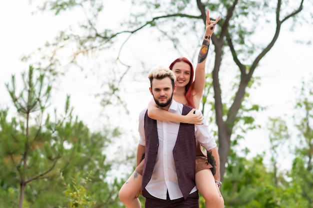 Pareja elegante enamorada caminando en el parque y abrazándose Encantadora pareja hipster divirtiéndose Amor juvenil y concepto de estilo de vida