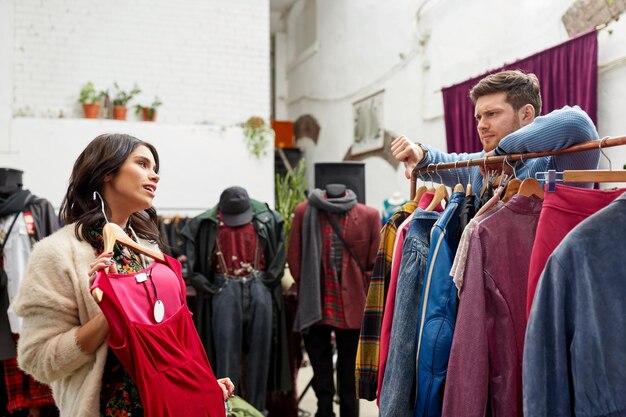 Foto una pareja eligiendo ropa en una tienda de ropa vintage.