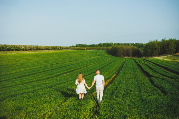 Pareja embarazada abrazándose en un campo verde de primavera Futuros padres en el parque de árboles con flores blancas Una pareja romántica esperando un bebé Un paseo por un campo verde