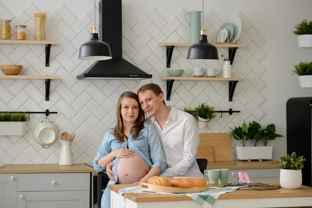 Pareja embarazada enamorada sentada en la cocina