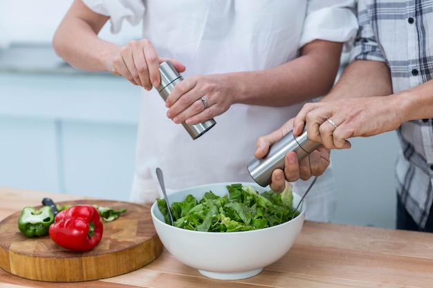 Pareja embarazada preparando ensalada en la cocina