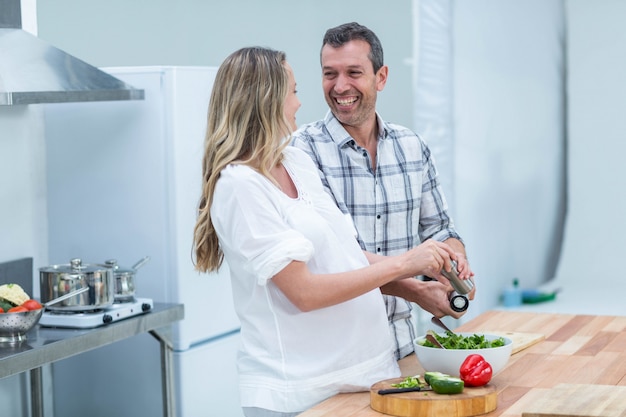 Pareja embarazada preparando ensalada en la cocina