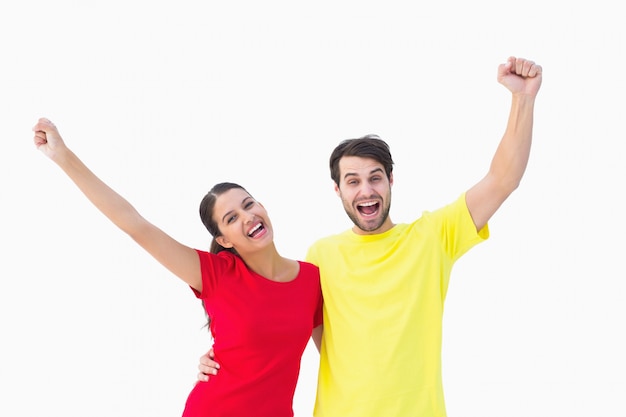 Pareja emocionada animando en camisetas rojas y amarillas