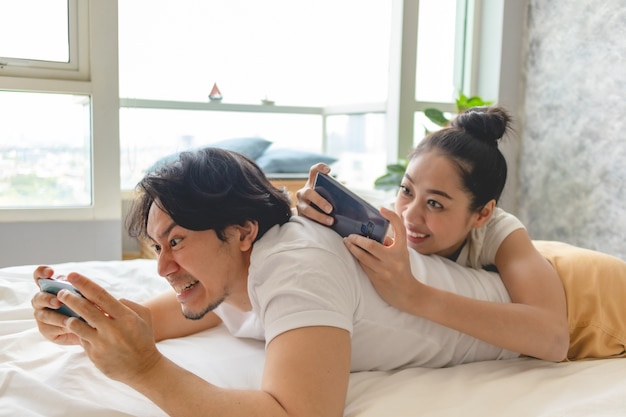 La pareja emocionada está jugando juntos al teléfono móvil en su apartamento.