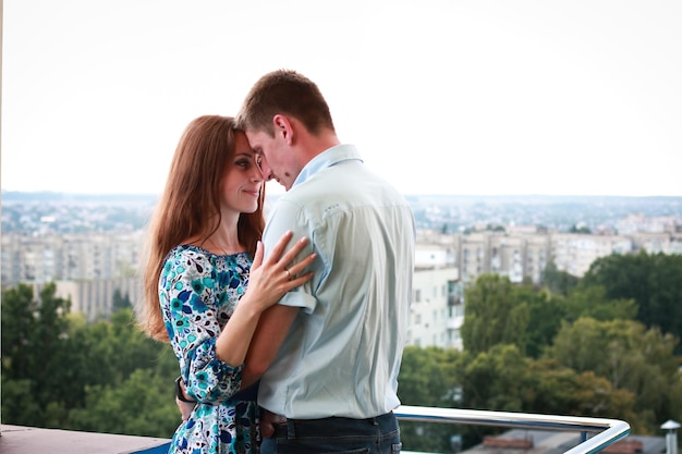 Una pareja enamorada al atardecer en el techo de un edificio de gran altura Copiar espacio