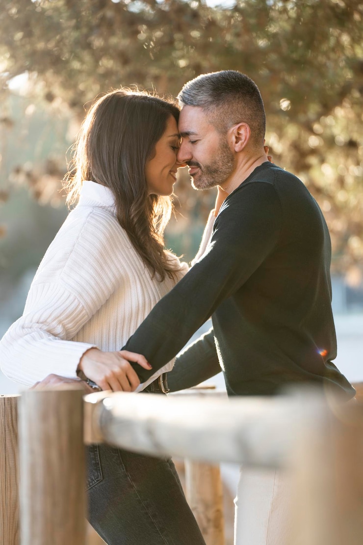 Foto una pareja enamorada bajo un árbol cerca de la playa con la puesta de sol al fondo