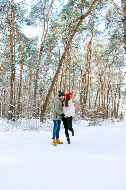 Una pareja enamorada camina por el bosque de invierno y se divierte. Marco vertical