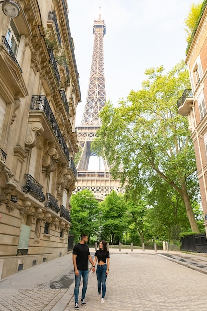 Pareja enamorada caminando de la mano con la Torre Eiffel detrás de ellos en París