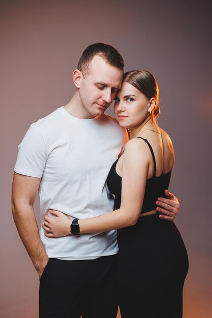 Una pareja enamorada con camisas blancas se abraza y se disfruta Una pareja elegante se abraza sobre un fondo blanco Concepto de familia feliz