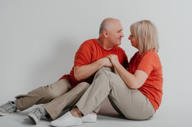 pareja enamorada con camisetas naranjas riéndose y abrazándose en un fondo blanco