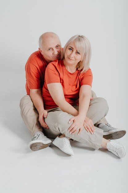 pareja enamorada con camisetas naranjas riéndose y abrazándose en un fondo blanco