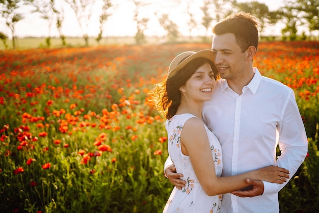 Una pareja enamorada en el campo de amapolas al atardecer disfrutando del tiempo juntos amor y estilo de vida