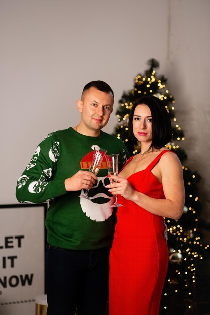 Una pareja enamorada celebra el Año Nuevo juntos cerca del árbol de Navidad Colores rojo y verde