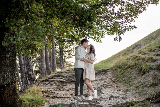 Una pareja enamorada, un chico y una chica están parados en el bosque y besándose