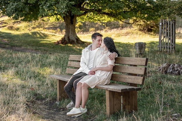 Una pareja enamorada, un chico y una chica se sientan en un banco y se acarician, se besan