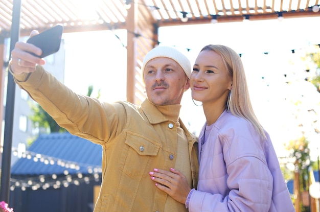 Una pareja enamorada, un chico y una chica, se toman una selfie juntos cuando hace sol