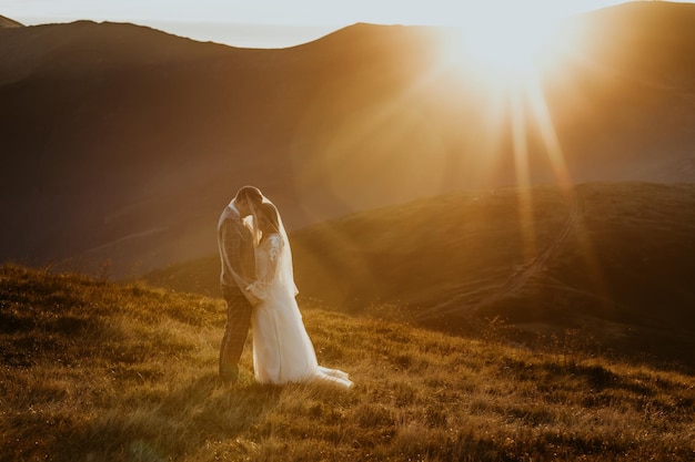 pareja enamorada, un chico y una chica vestidos de boda están parados en las montañas