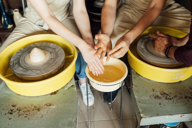 Foto una pareja enamorada crea una copa conjunta en un taller de cerámica alfarero haciendo una vasija de cerámica en la alfarería...