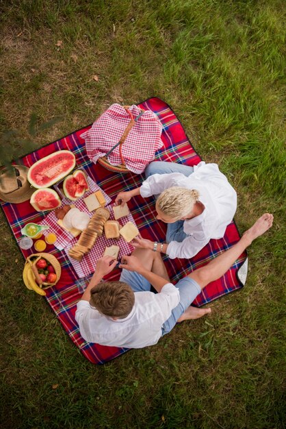 Pareja enamorada disfrutando de la comida y la bebida de la hora del picnic en la hermosa naturaleza en la vista superior de la orilla del río