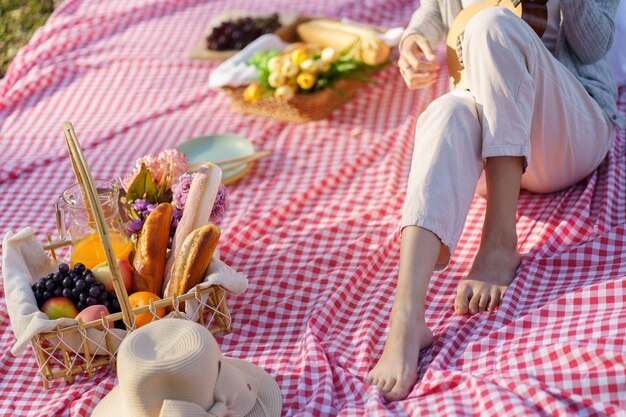 Pareja enamorada disfrutando de un picnic tocando la guitarra en el parque al aire libre Pareja feliz de picnic relajándose junto con una cesta de picnic