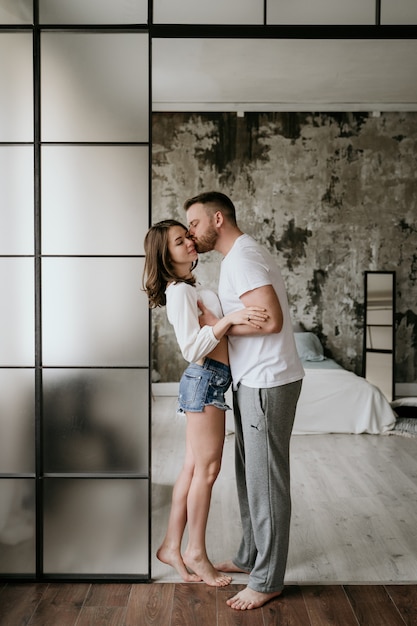 Pareja enamorada en el dormitorio. Morena esbelta. Interior con estilo.