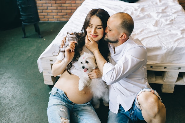 Pareja enamorada, embarazada, tumbada en la cama abrazada, esperando bebé