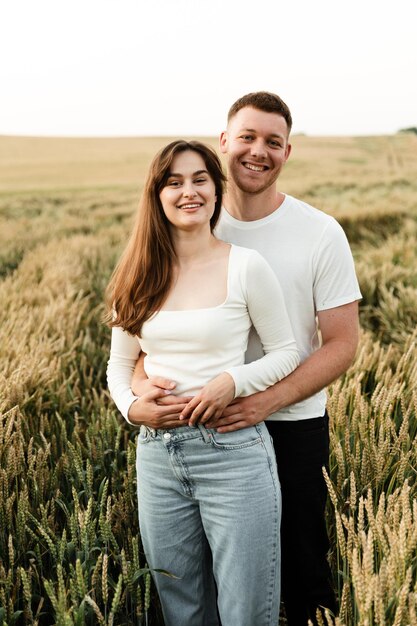 Una pareja enamorada se encuentra entre un campo de trigo y se toma de la mano. un chico y una chica caminan en la naturaleza. vacaciones fuera de la ciudad