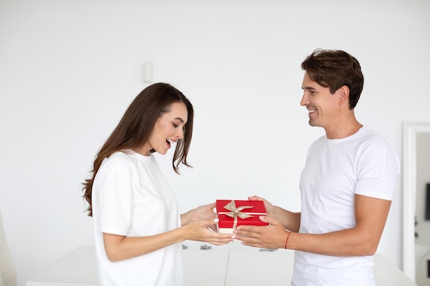 Pareja enamorada. El hombre sorprende a su novia con un regalo en casa.