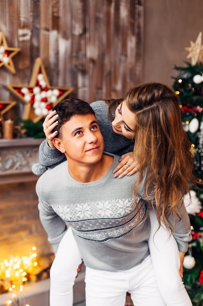 Pareja enamorada junto a la chimenea y el árbol de Navidad chico y chica i