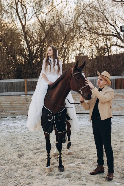 Pareja enamorada montando caballos en el rancho al atardecer en invierno